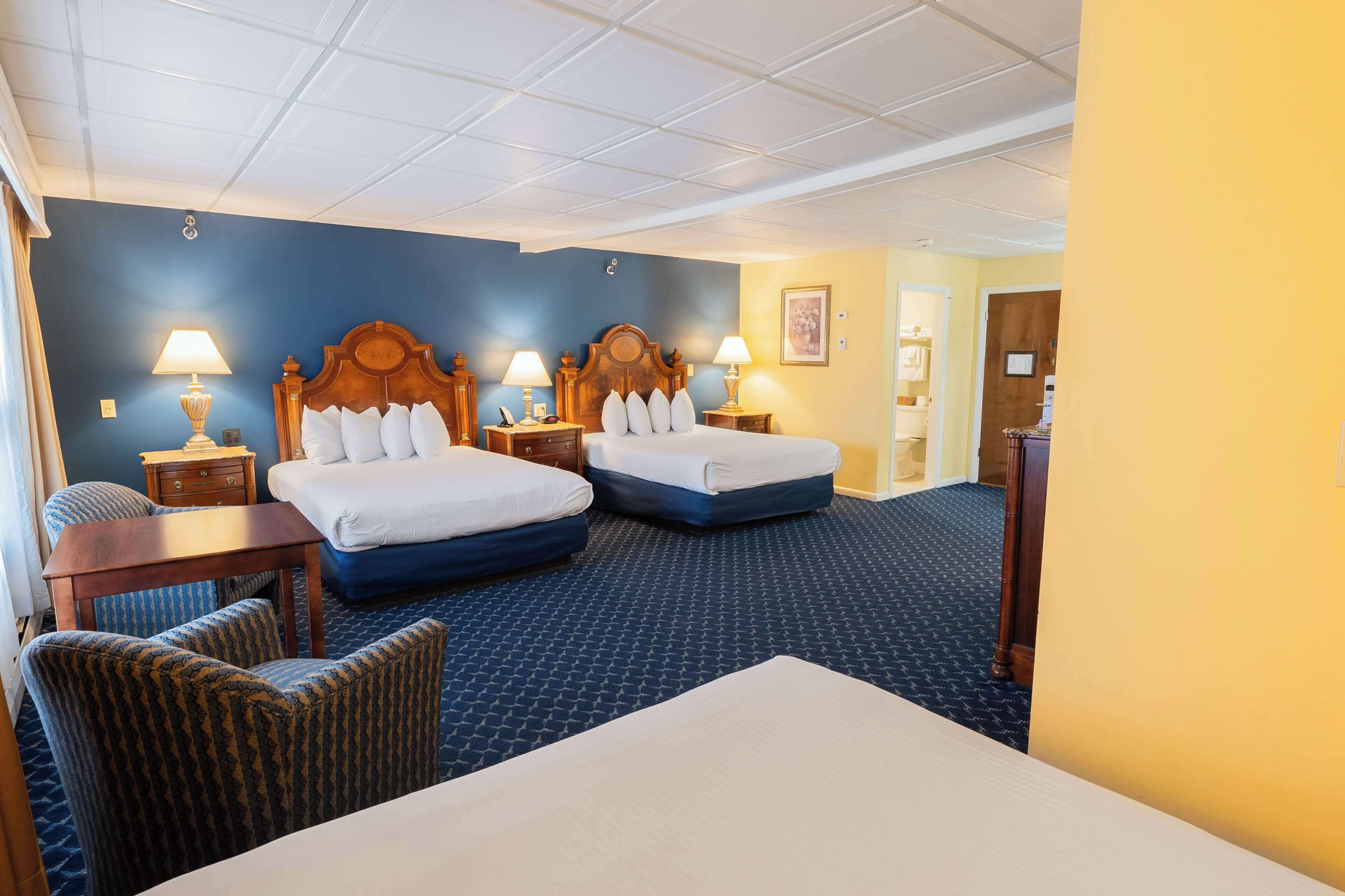 A hotel room with two beds, a desk, and a chair.