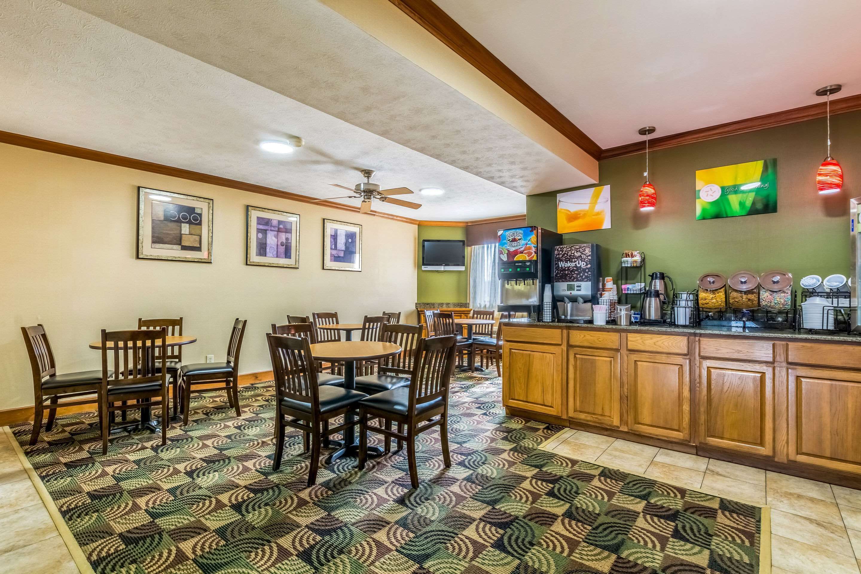 A dining area with wooden tables and chairs, a kitchen counter with appliances, and a patterned rug.