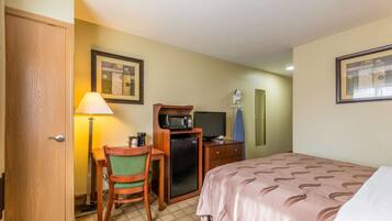 Une chambre d’hôtel comprenant un lit, un bureau avec une chaise, un four à micro-ondes, une télévision et une porte.