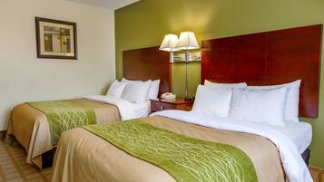 A hotel room with two beds, a nightstand, a lamp, and a framed picture on the wall.