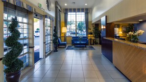 A hotel lobby with a reception desk, seating area, and large windows. - Ramada by Wyndham Costa Mesa/Newport Beach (Costa Mesa)