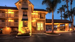 A hotel with a central tower, multiple balconies, and a parking area. - Ramada by Wyndham Costa Mesa/Newport Beach (Costa Mesa)