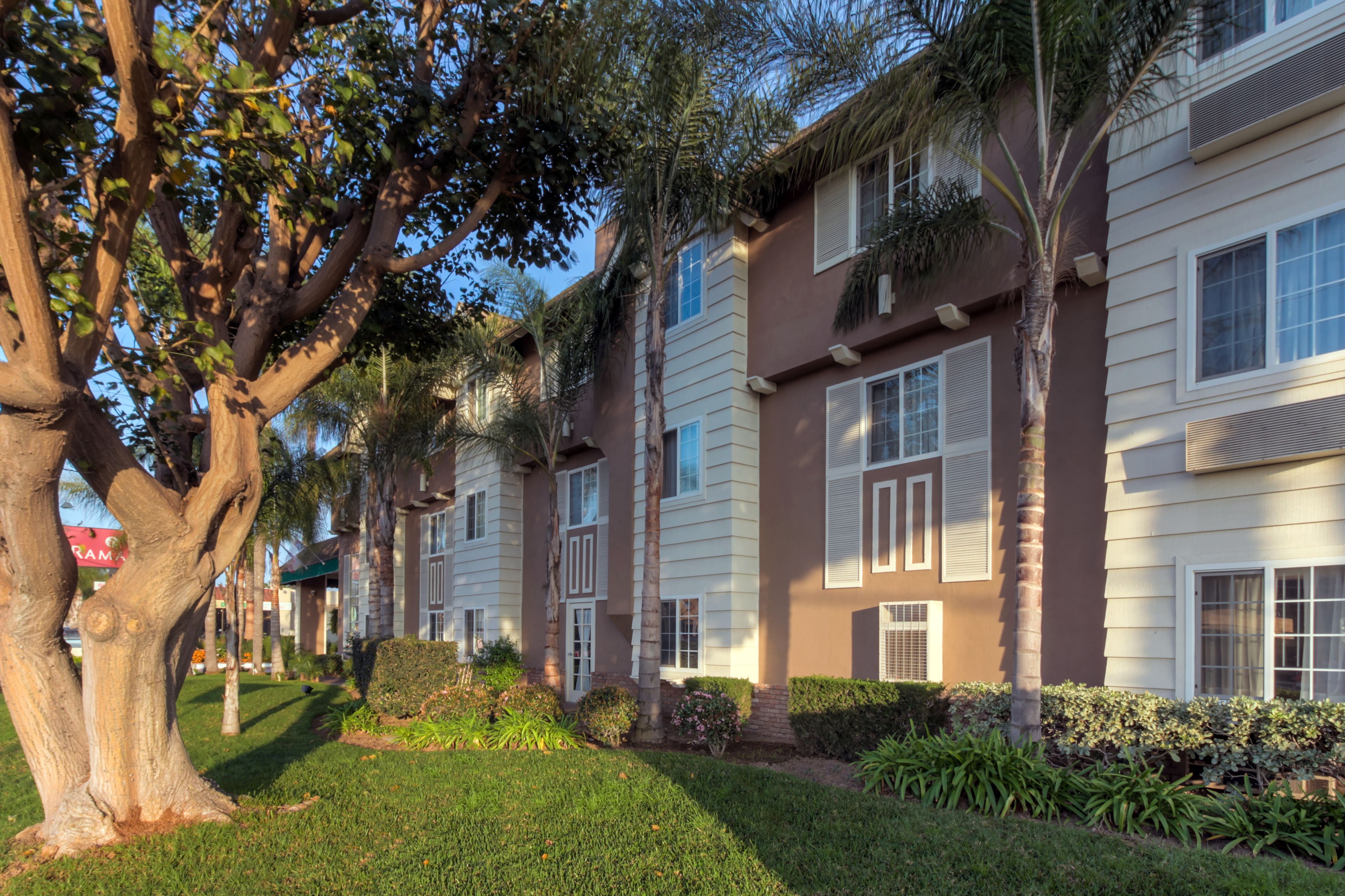 A row of two-story residential buildings with a well-maintained lawn and mature trees.