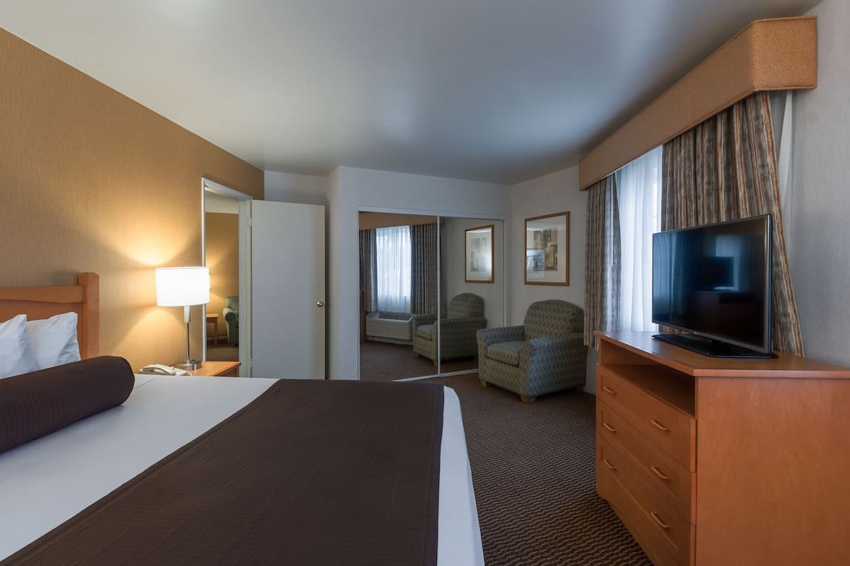 Ein Hotelzimmer mit Bett, Fernseher, Kommode, Sessel und Schreibtisch.