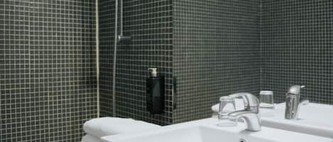 A bathroom with a white sink, a shower, and a tiled wall.