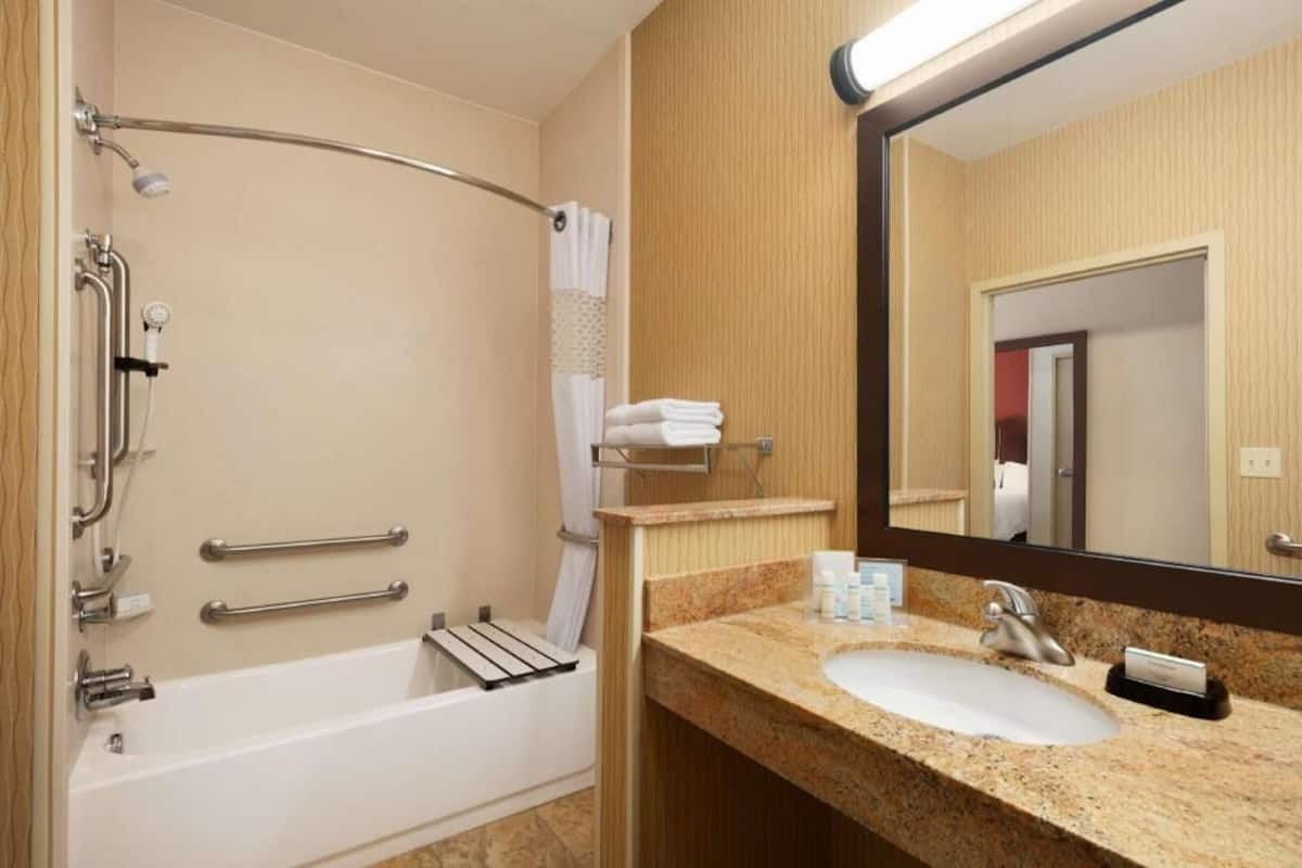 A bathroom with a bathtub, a sink, a mirror, and a towel rack.