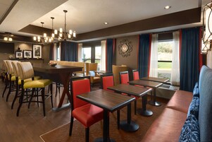 A restaurant with multiple dining tables and chairs, a bar area, and a seating section with sofas and chairs.