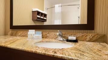 A bathroom with a granite countertop, a sink, a mirror, a towel rack, and a shower curtain.