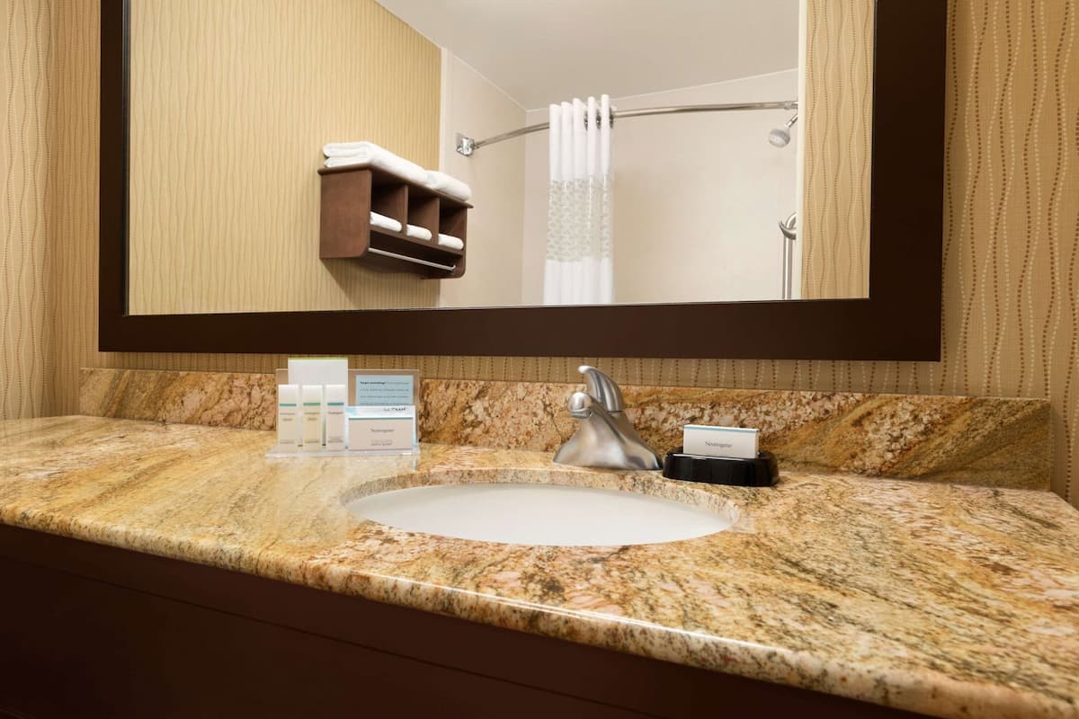 A bathroom with a marble sink, a mirror, a towel rack, and toiletries.