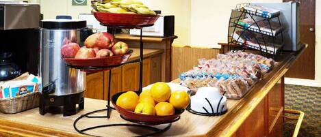 A buffet counter with fruits, sandwiches, and beverages.