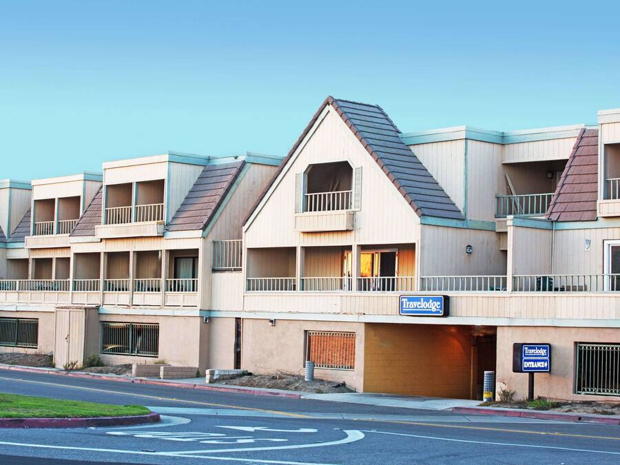 Uma fileira de edifícios do hotel Travelodge, com várias varandas e céu claro.
