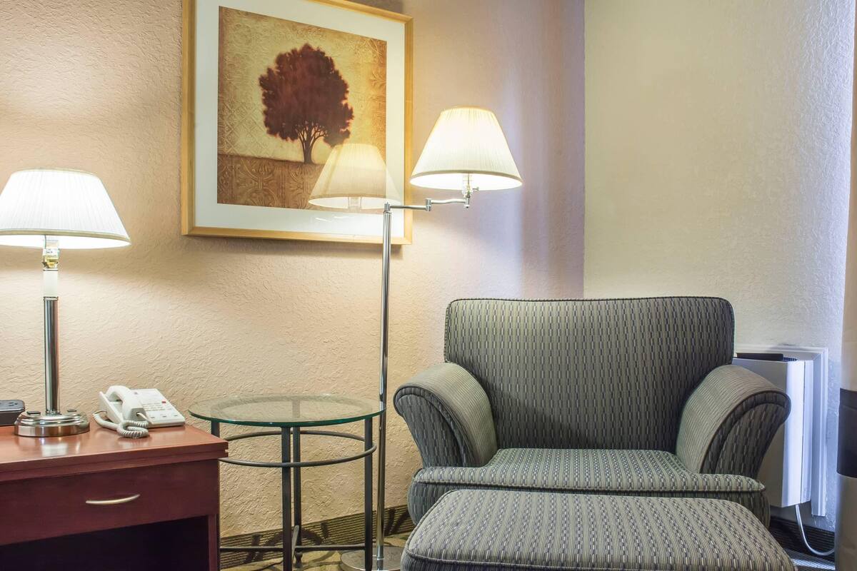 A hotel room with a sofa, two lamps, a small table, a phone, and a framed picture on the wall.
