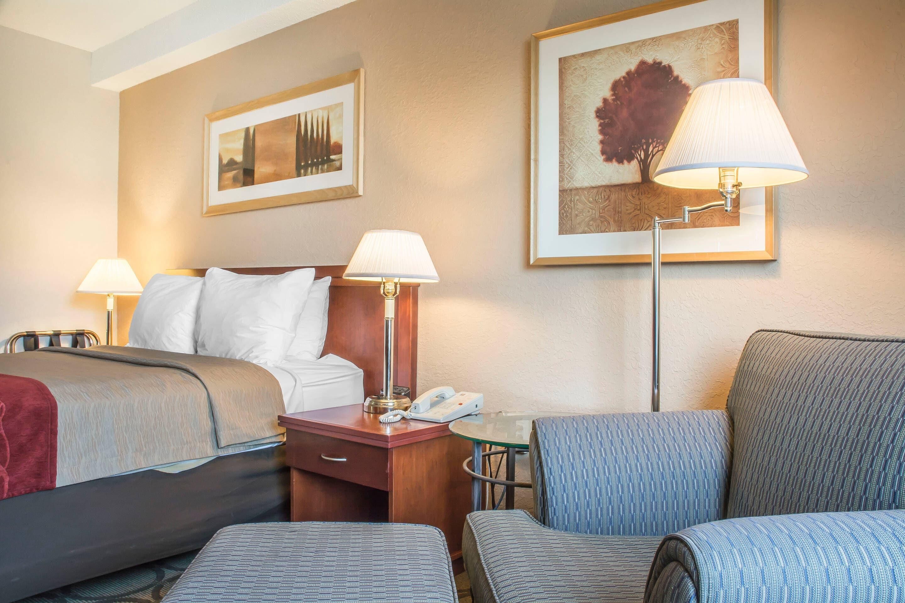 A hotel room with a bed, two bedside tables, a desk, a chair, and two lamps.