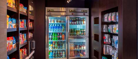 Espaço de máquinas automáticas com opções de lanches e bebidas, incluindo batatas, refrigerantes e água engarrafada.