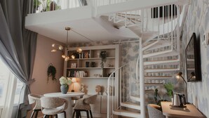A modern interior with a spiral staircase, a dining area with chairs, and a bookshelf. - Home Hotel Skagen Brygge (Stavanger)