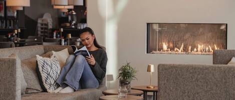 A cozy living room with a sofa, a small table with a plant, and a fireplace.