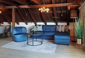 Ein modernes Wohnzimmer mit einem blauen Modulsofa, einem runden Couchtisch und einer Pendelleuchte.