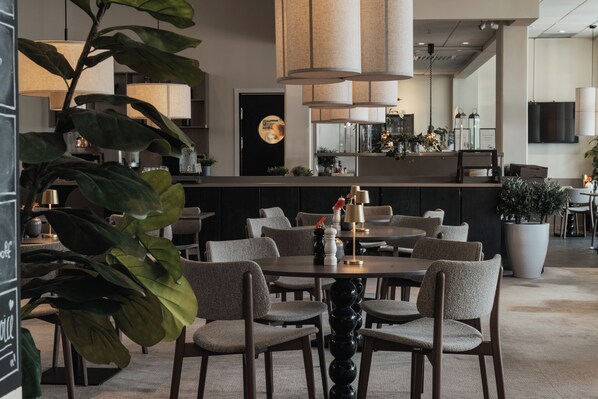 Un comedor moderno con mesas redondas, sillas e iluminación colgante.