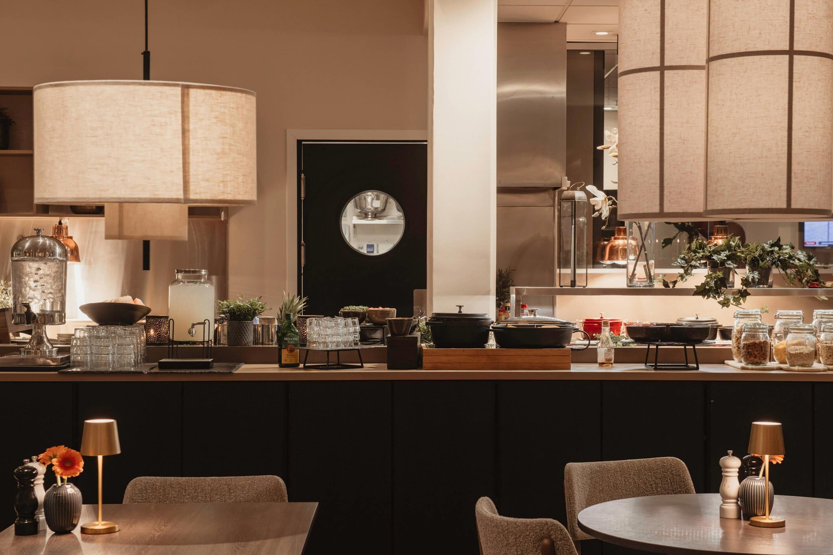 A modern kitchen with a round island, pendant lighting, and a black door with a circular mirror.