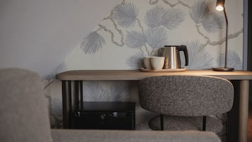 Quarto moderno com uma escrivaninha, uma cadeira, um abajur e uma cafeteira.