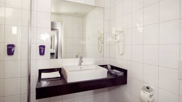 A modern bathroom with a large mirror, a white sink, and a black countertop.