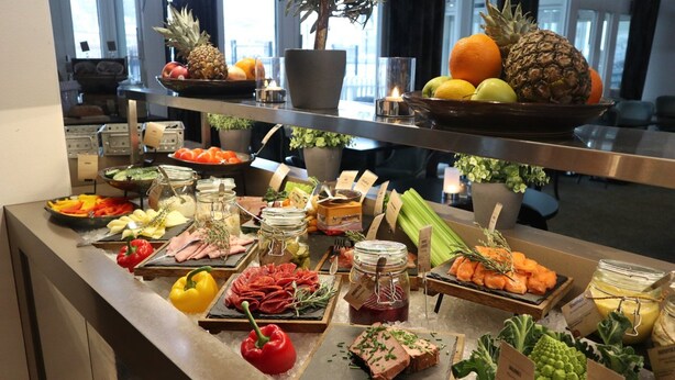 A buffet with various food items, including fruits, vegetables, and meats, displayed on a counter. - Home Hotel Skagen Brygge (Stavanger)