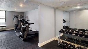 Ein Fitnessraum mit Laufband, Gewichtbank und Kurzhanteln.