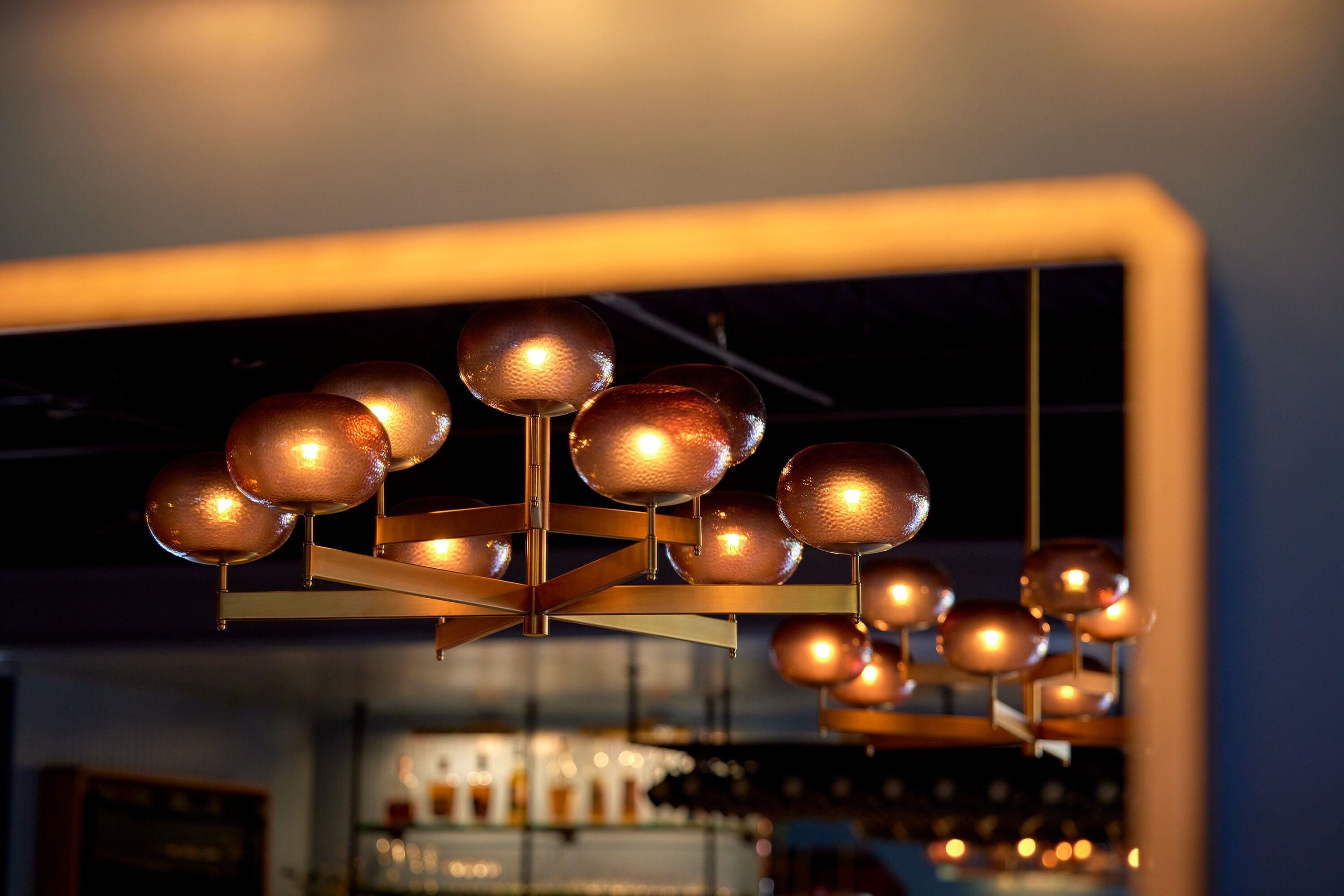 A chandelier with multiple spherical lights in a bar setting.