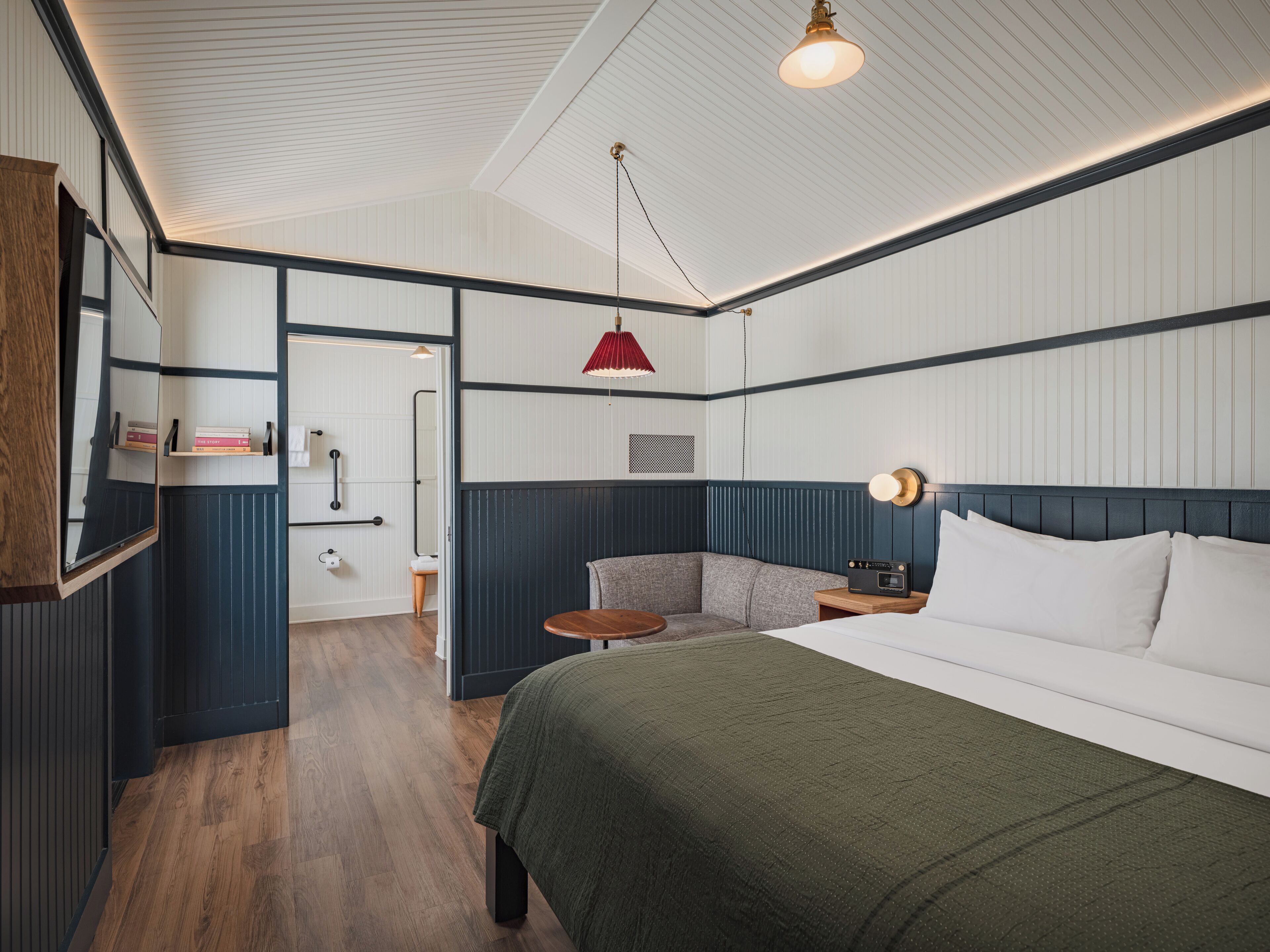 Habitació d'hotel amb un llit gran, una zona de seients petita, un aparell de ràdio i un mirall.