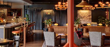 Un moderno vestíbulo de hotel con una zona de bar, asientos y un cuadro grande en la pared.