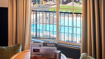 Ein Zimmer mit Fensterblick auf einen Pool, einem Radio und einem Holztisch mit Tablett.
