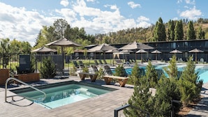 A pool area with lounge chairs, umbrellas, and a pool with a diving board. - High Country Motor Lodge – Near NAU/Downtown (Flagstaff)