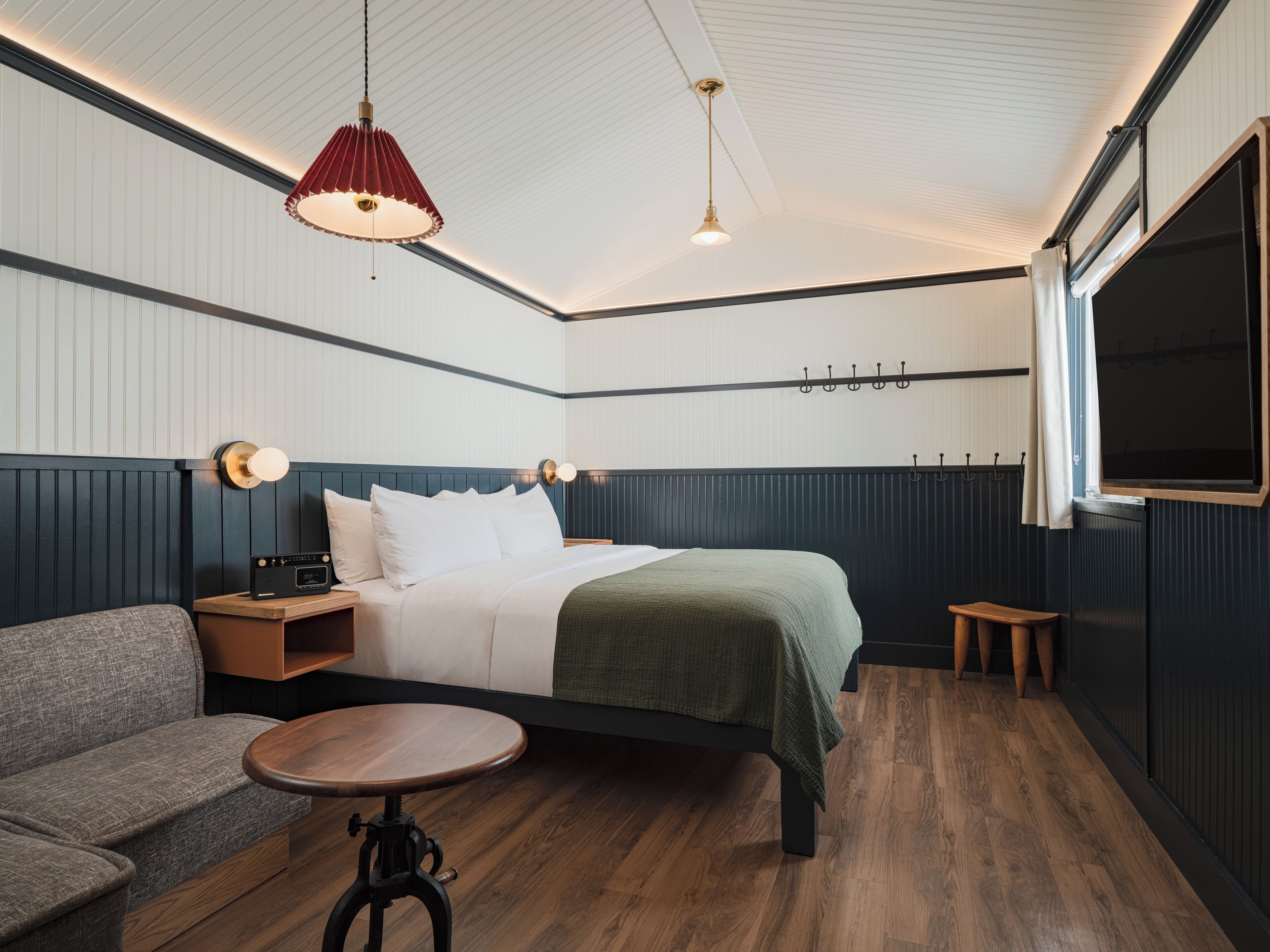 A modern hotel room with a bed, a sofa, a small table, and a TV.