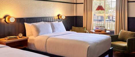 A hotel room with a large bed, two bedside tables with lamps, a chair, and a view of the outside.