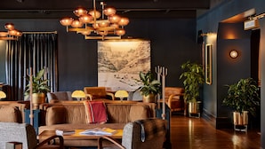 A modern lounge area with a large wall mural, comfortable seating, and ambient lighting. - High Country Motor Lodge – Near NAU/Downtown (Flagstaff)