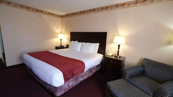 A hotel room with a large bed, two bedside tables with lamps, and a patterned armchair.