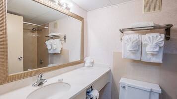 Un baño con un espejo grande, un lavabo, un inodoro y un perchero para toallas.