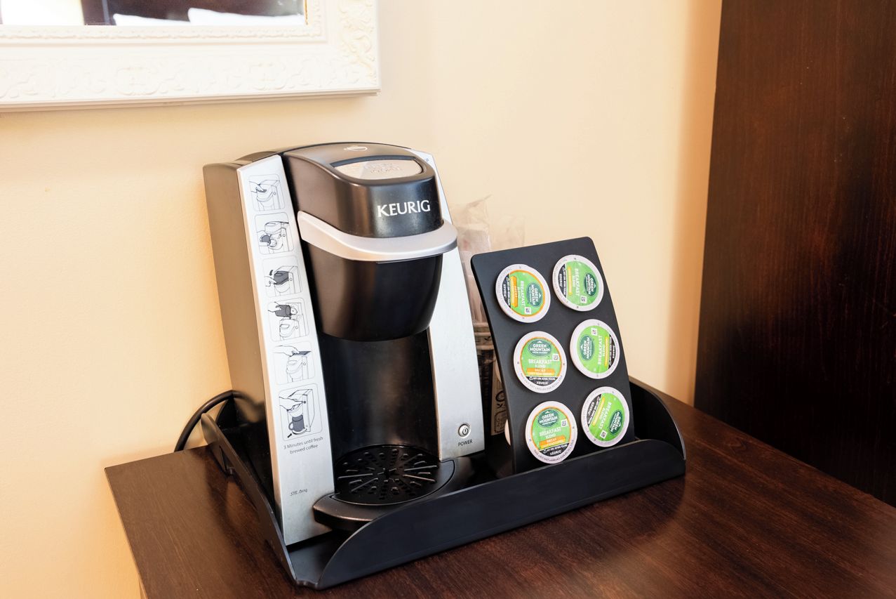 A Keurig coffee machine with a coffee pod holder on a wooden table.