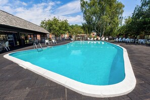 A swimming pool with a tiled deck, surrounded by lounge chairs and a covered seating area. - Fireside Inn & Suites Portland (Portland)
