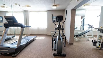 Un gimnasio con cinta de correr, elíptica y máquinas de pesas.