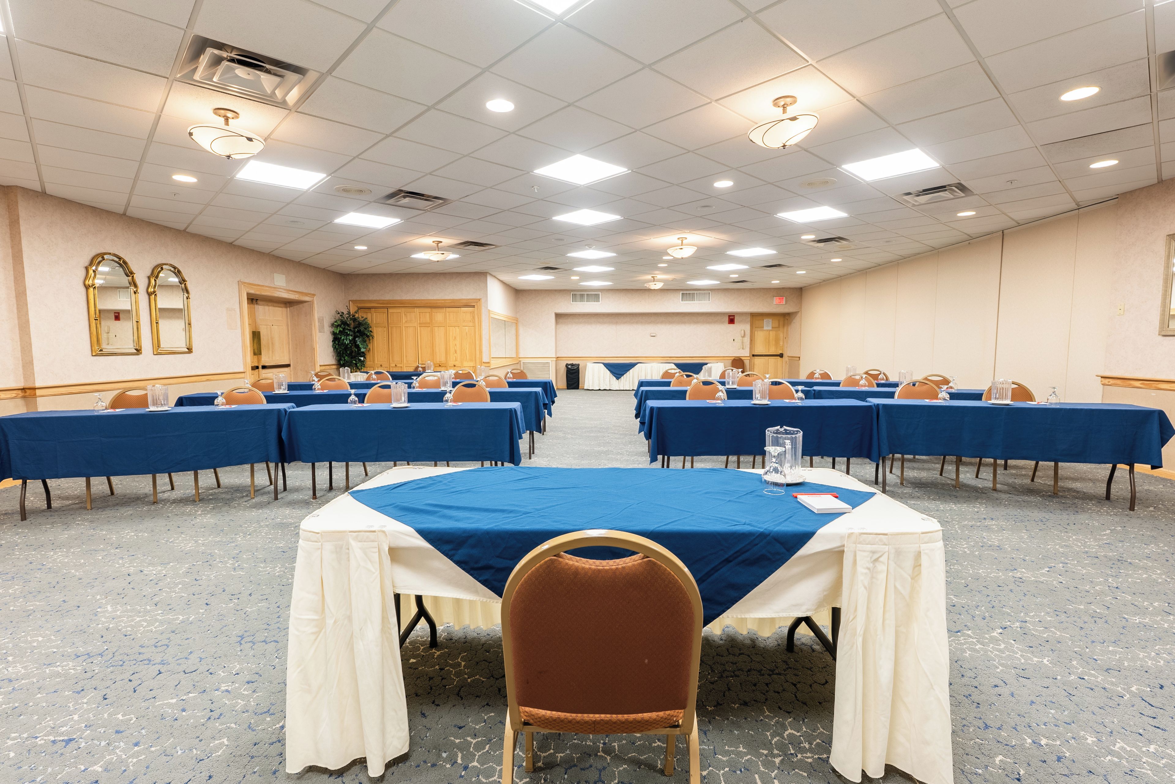 A conference room with multiple tables, chairs, and a large whiteboard.