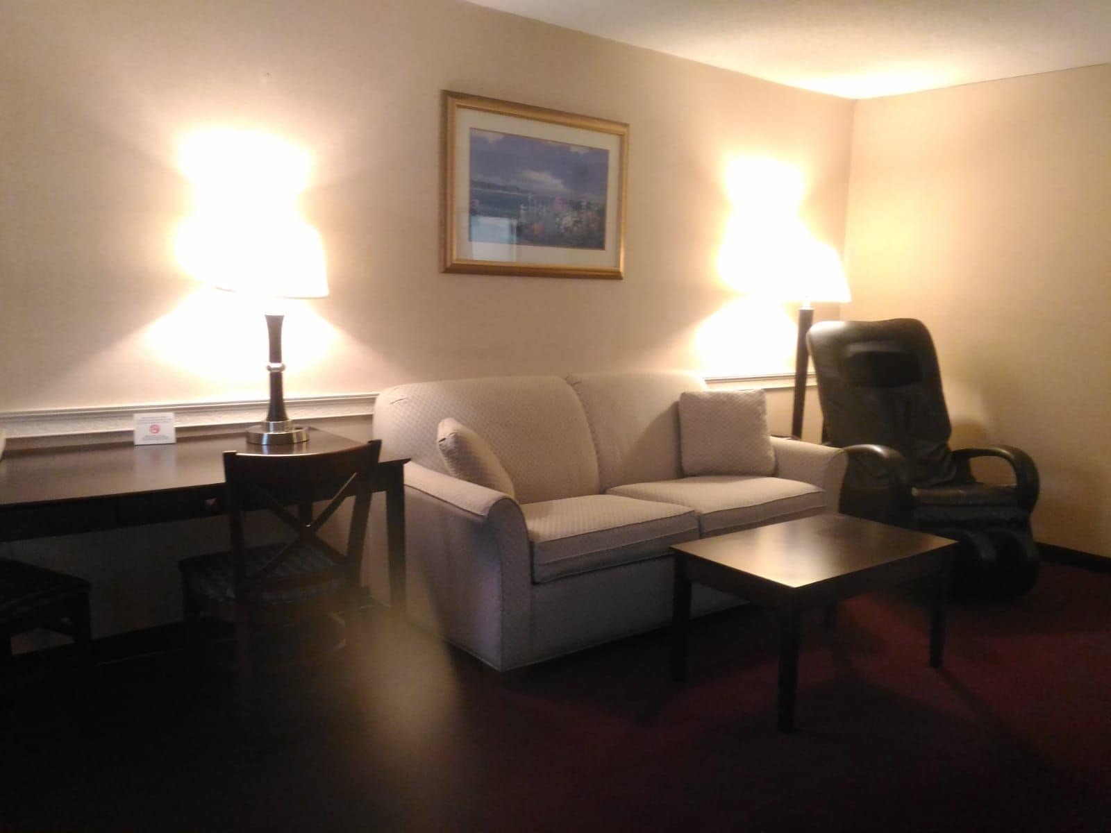 Un salon comprenant un canapé, une table basse, un bureau et deux lampes.