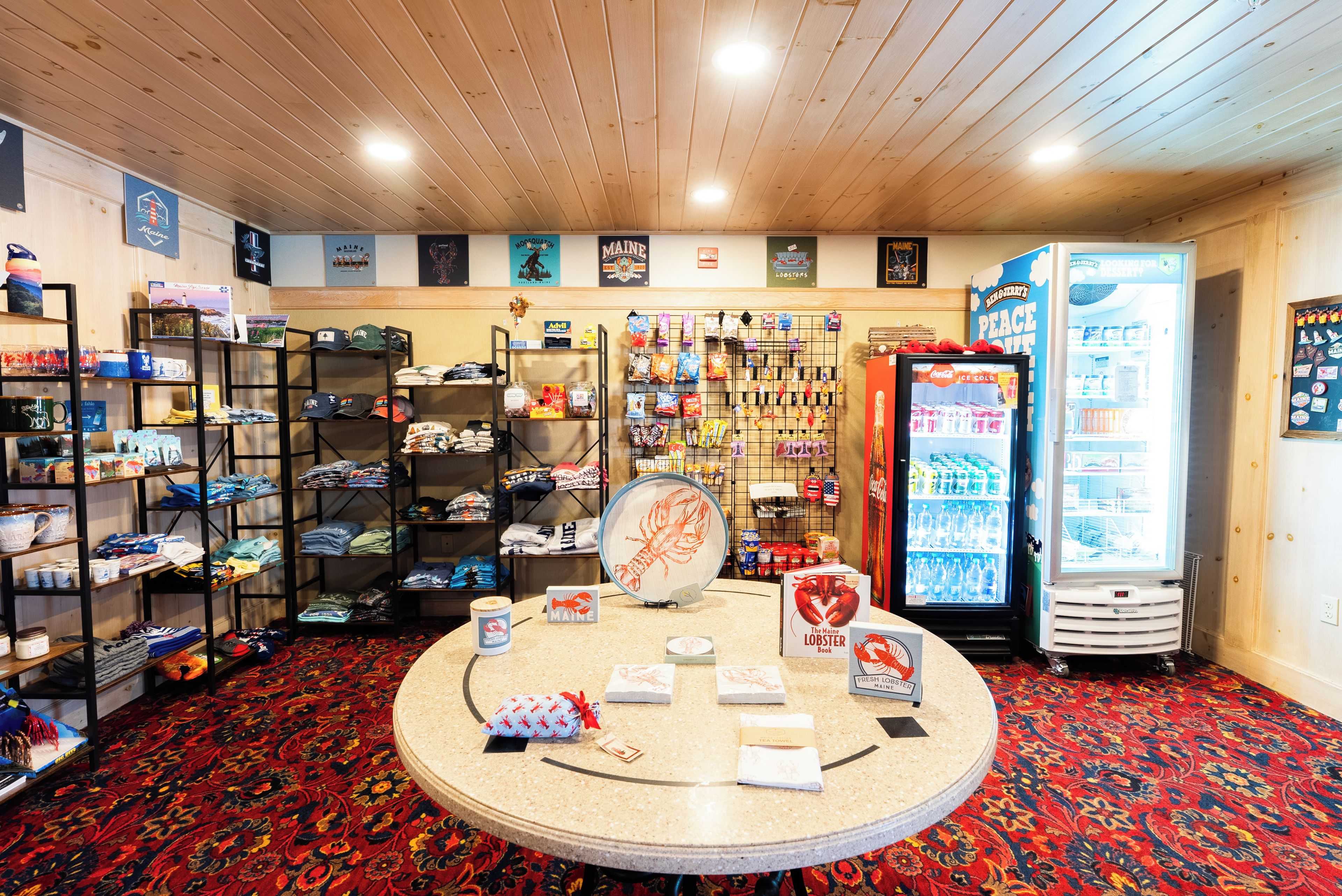 Un espacio comercial con estanterías llenas de mercancía, una mesa de exhibición con artículos promocionales y un refrigerador con bebidas.