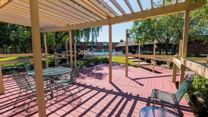 A covered outdoor patio with a pool, green metal chairs, and a wooden pergola. - Fireside Inn & Suites Portland (Portland)
