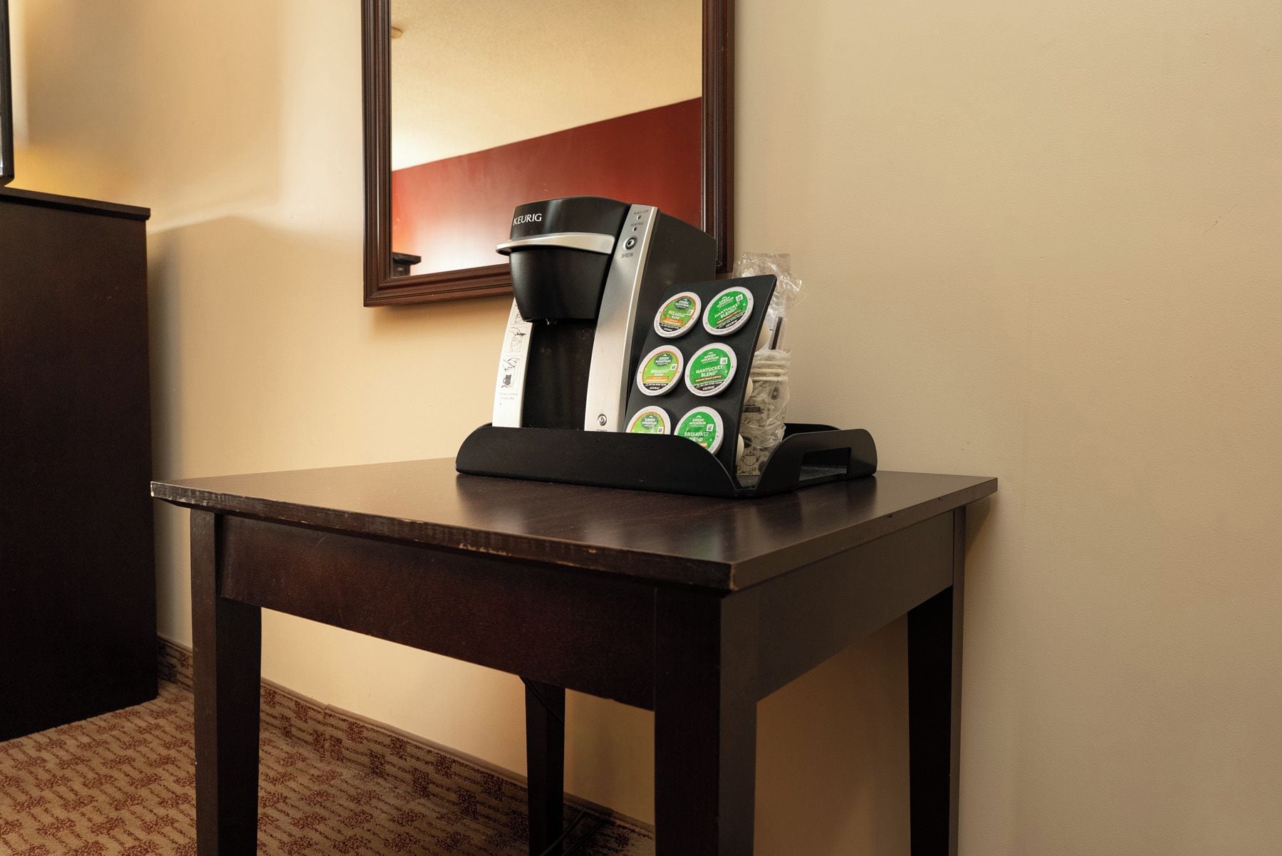 A coffee machine with a drip tray and a coffee pod holder on a dark wooden table.