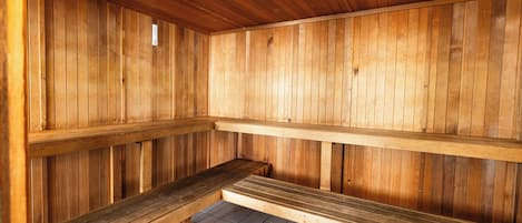 A wooden sauna with benches and a tiled floor.
