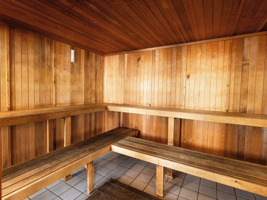 Una sauna de madera con bancos y piso de baldosas.