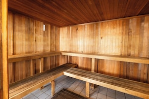 Una sauna de madera con bancos y piso de baldosas.