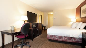 A hotel room with a bed, desk, chair, television, and a microwave.