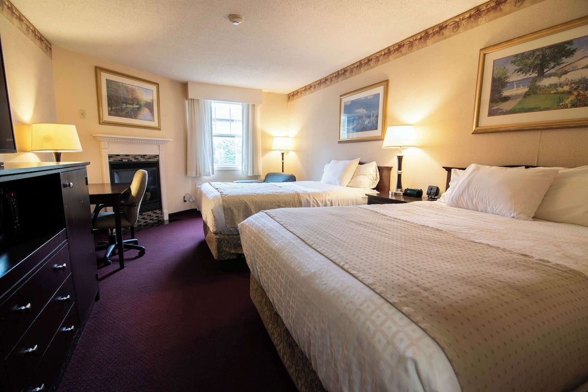 Quarto de hotel com duas camas, uma escrivaninha, uma cadeira e uma televisão.